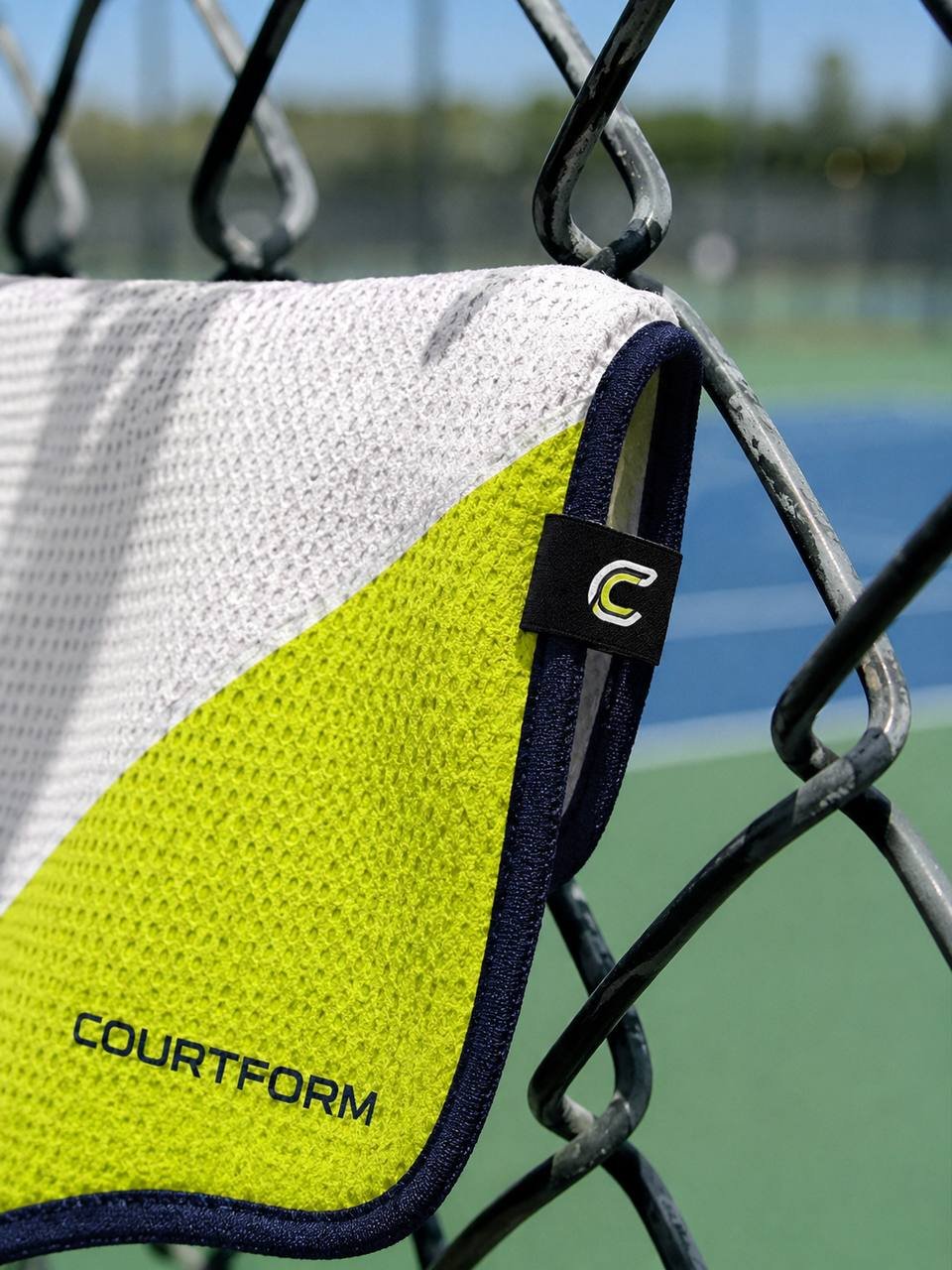 Courtform Pro towel close-up on chain-link fence with C logo magnetic attachment