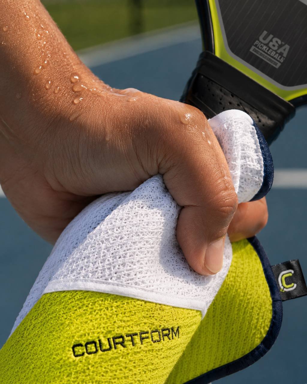 Player wiping sweat off palm with Courtform Pro palm-dry corner before serve